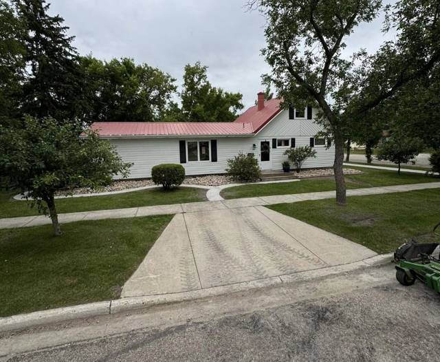 Freshly mowed corner lot with rock beds in front of a house with a red metal roof