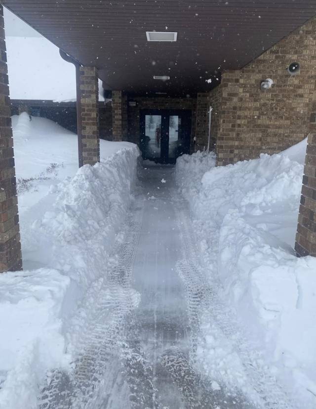 Cleared walkway to a building entrance between high snowbanks