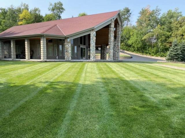 Freshly striped lawn in front of a home with stone pillars